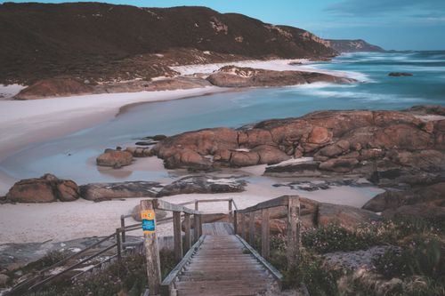 Free Long exposure of narrow wooden stairway leading to rocky vast seacoast washed by blue wavy seawater in early evening Stock Photo