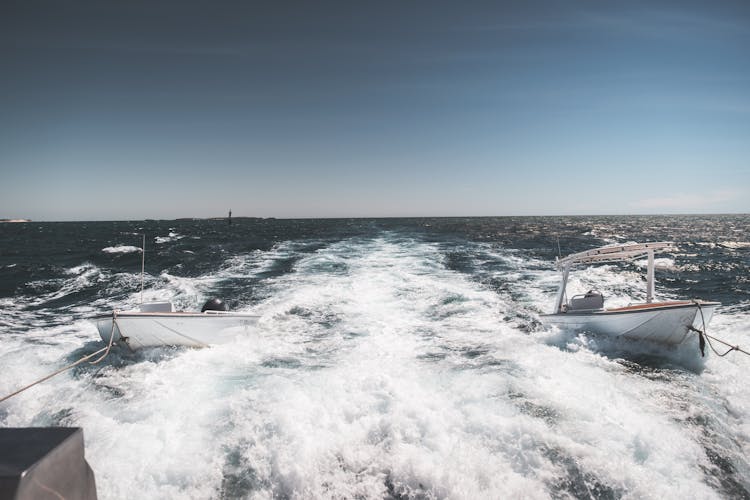 Yacht Pulling Motorboats On Foamy Seawater