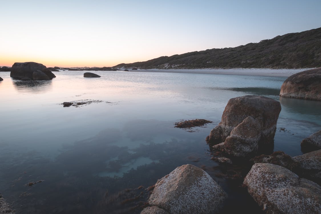 Rocky seashore with calm seawater at twilight