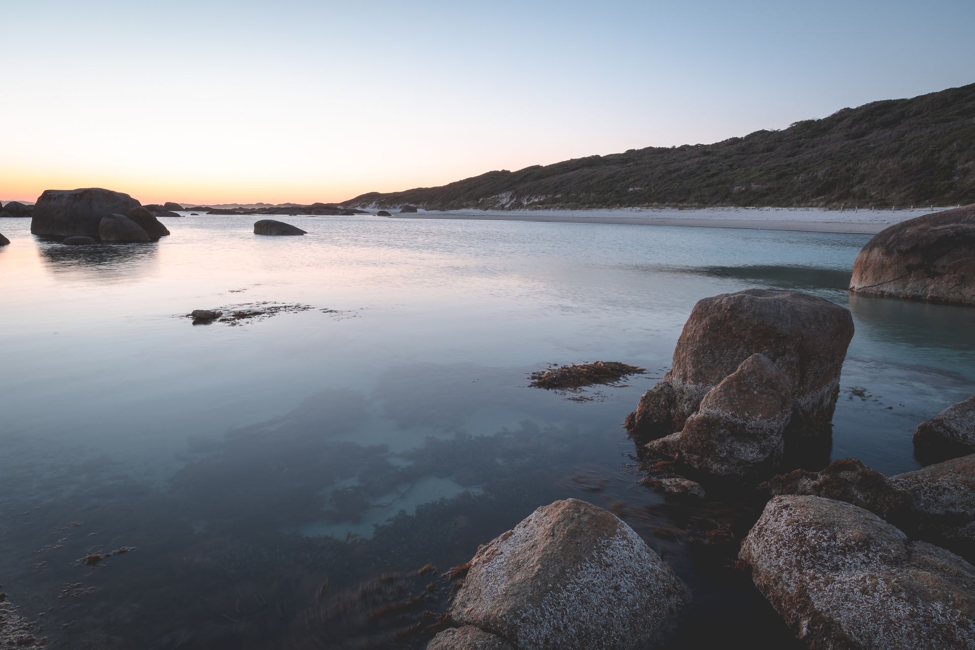 Peaceful seaside scene at twilight featuring calm waters and rugged rocky shores. Perfect for serene environments.