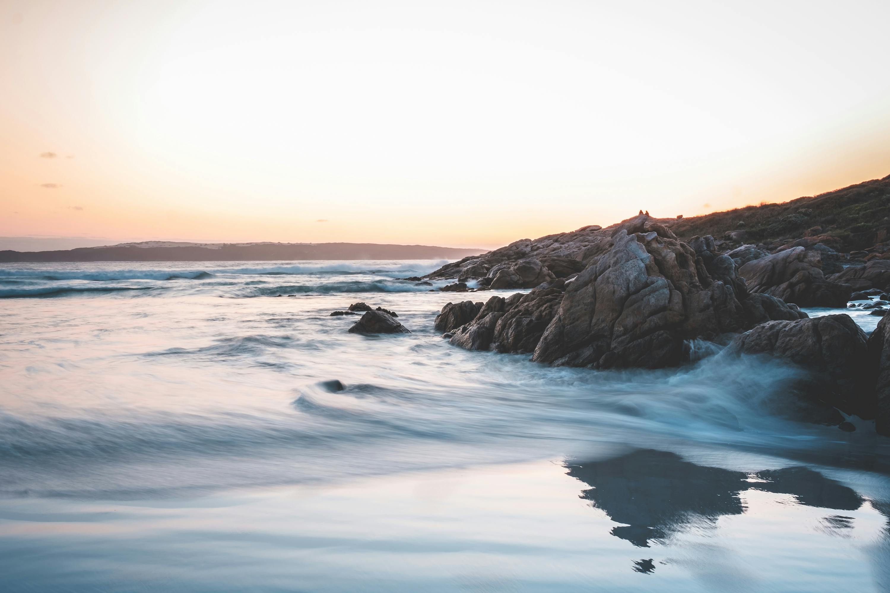 美丽的日落天空下，泡沫波浪般的海水冲刷着粗糙的岩石海岸，风景优美