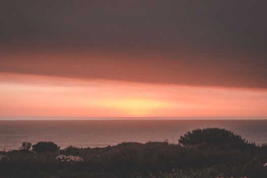 Breathtaking scenery of dark pink cloudy sunset sky over endless majestic sea in evening nature