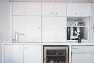 Interior of minimalist style kitchen with white furniture and steel appliances in modern boat