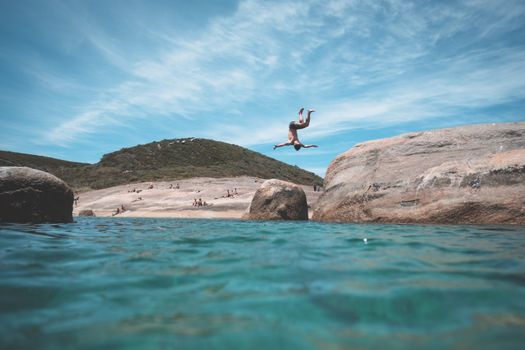 Anonymous man jumping into ocean during summer vacation