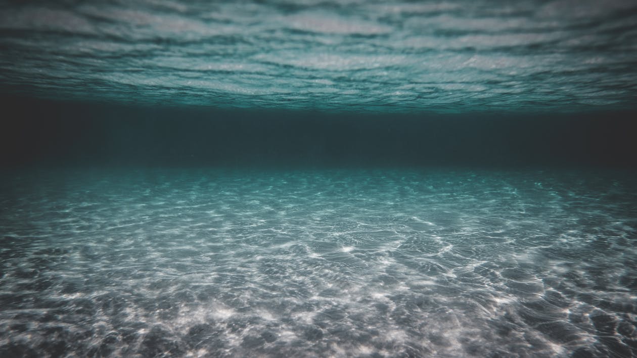 Turquoise clear water of wavy sea with sandy bottom on sunny day as abstract background