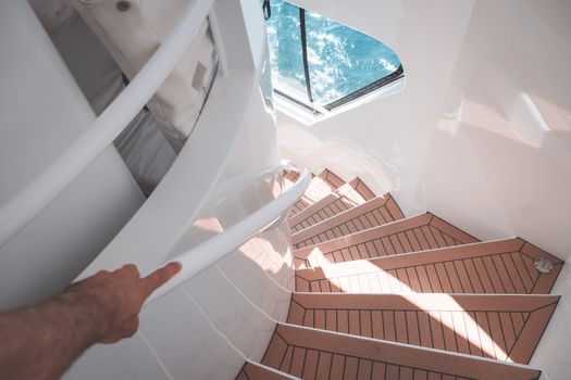 Anonymous man walking downstairs in modern boat during cruise