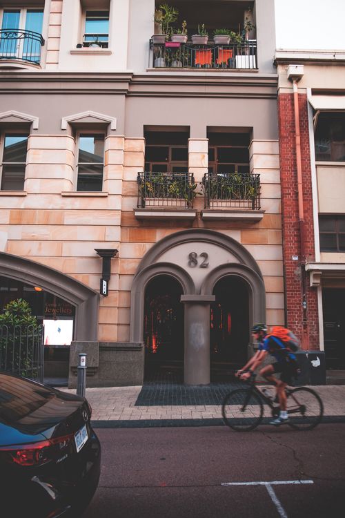 Free Side view of anonymous cyclist riding bicycle on modern street with contemporary residential house with balconies Stock Photo