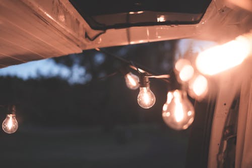 Row of shiny bright lamps hanging on garland decorating automobile on blurred background of nature