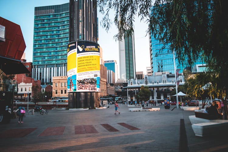 Modern City With Glass Buildings And Luminous Signboard With Advertisement