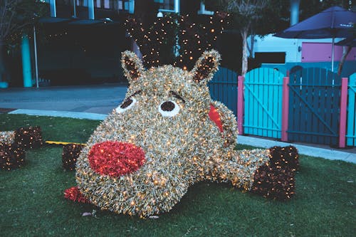Big funny figure of animal with red nose and shiny lights of garlands in playground