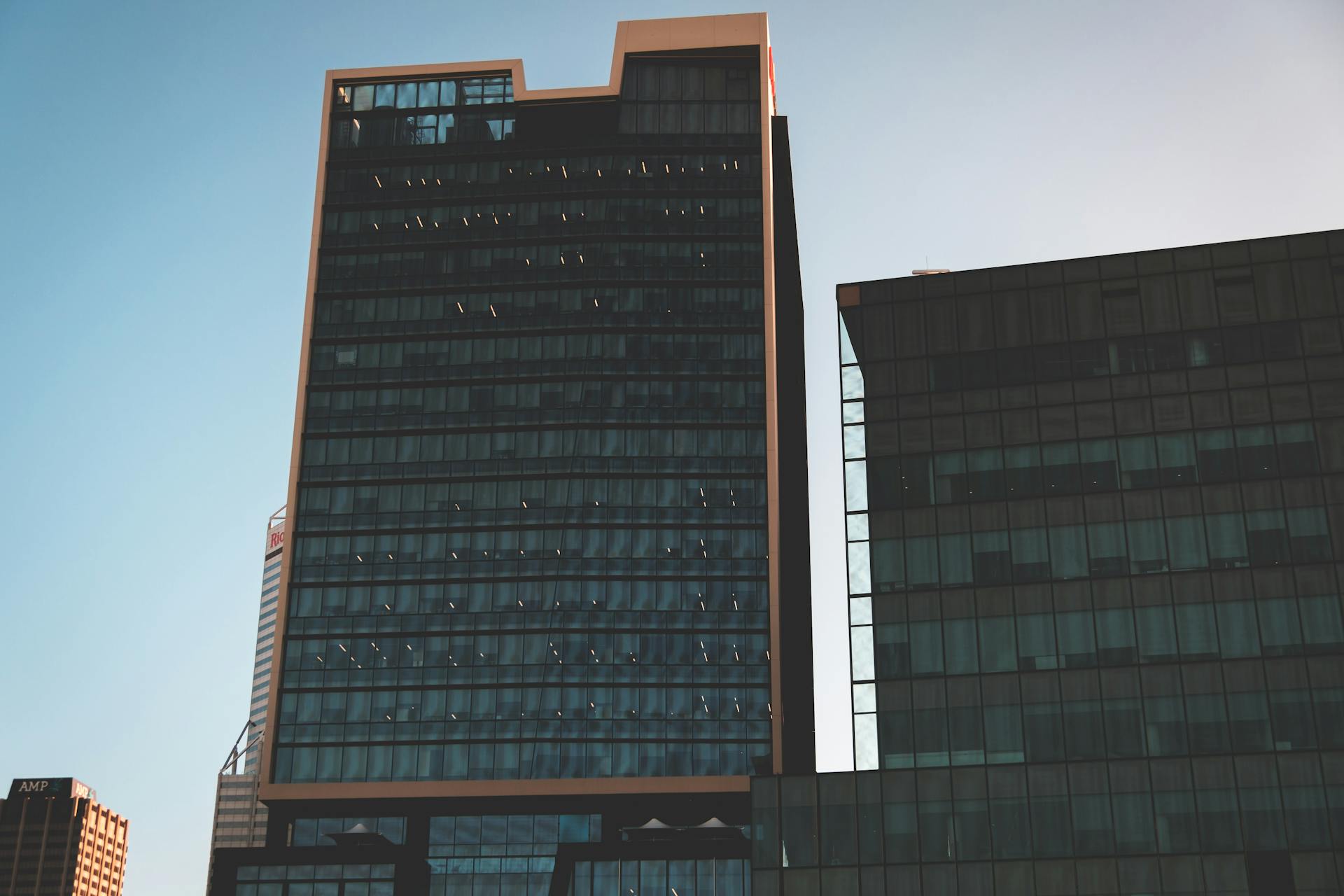 Modern tall huge buildings with glass exteriors under cloudless sunny sky in daytime