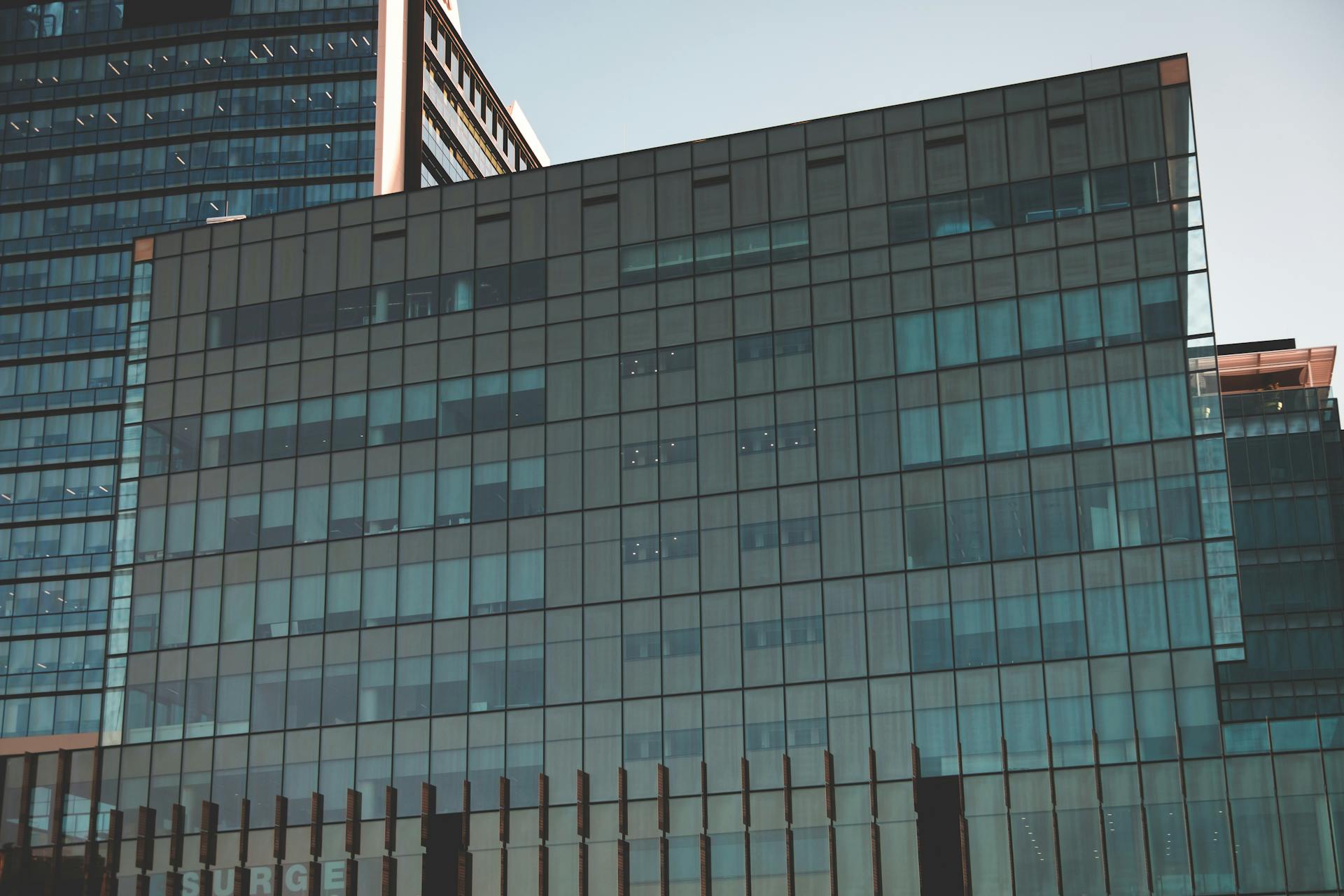 Contemporary glass office building with geometric facade in an urban setting.