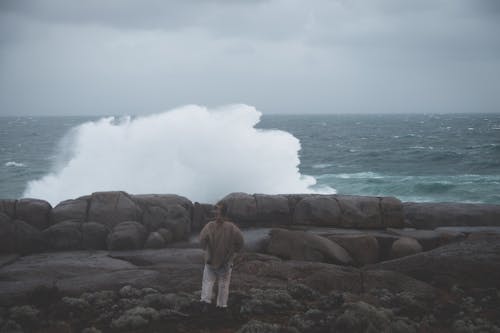 Person standing on rocky coast and looking at stormy sea