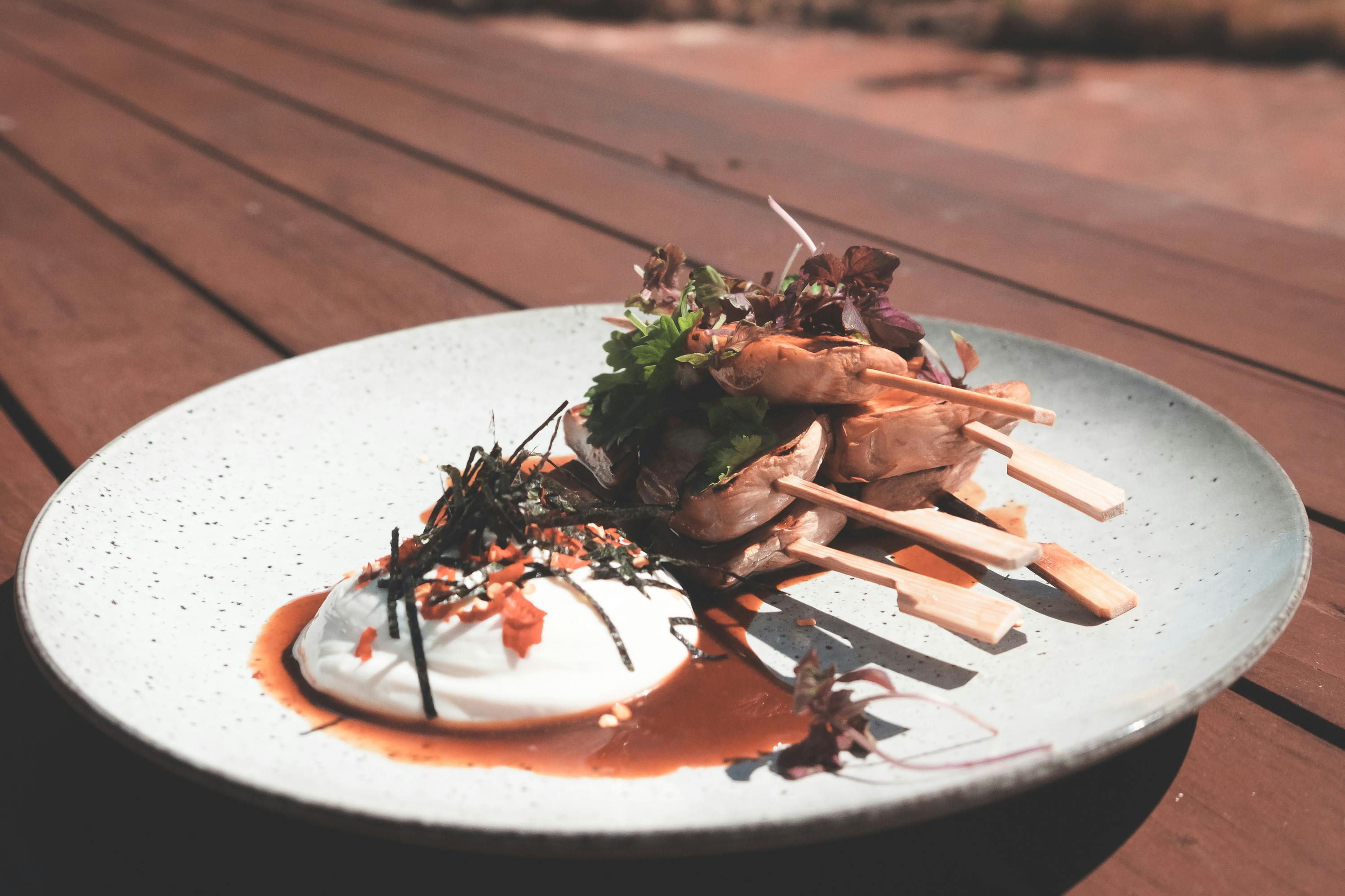 plate with meat pieces on sticks near poached egg