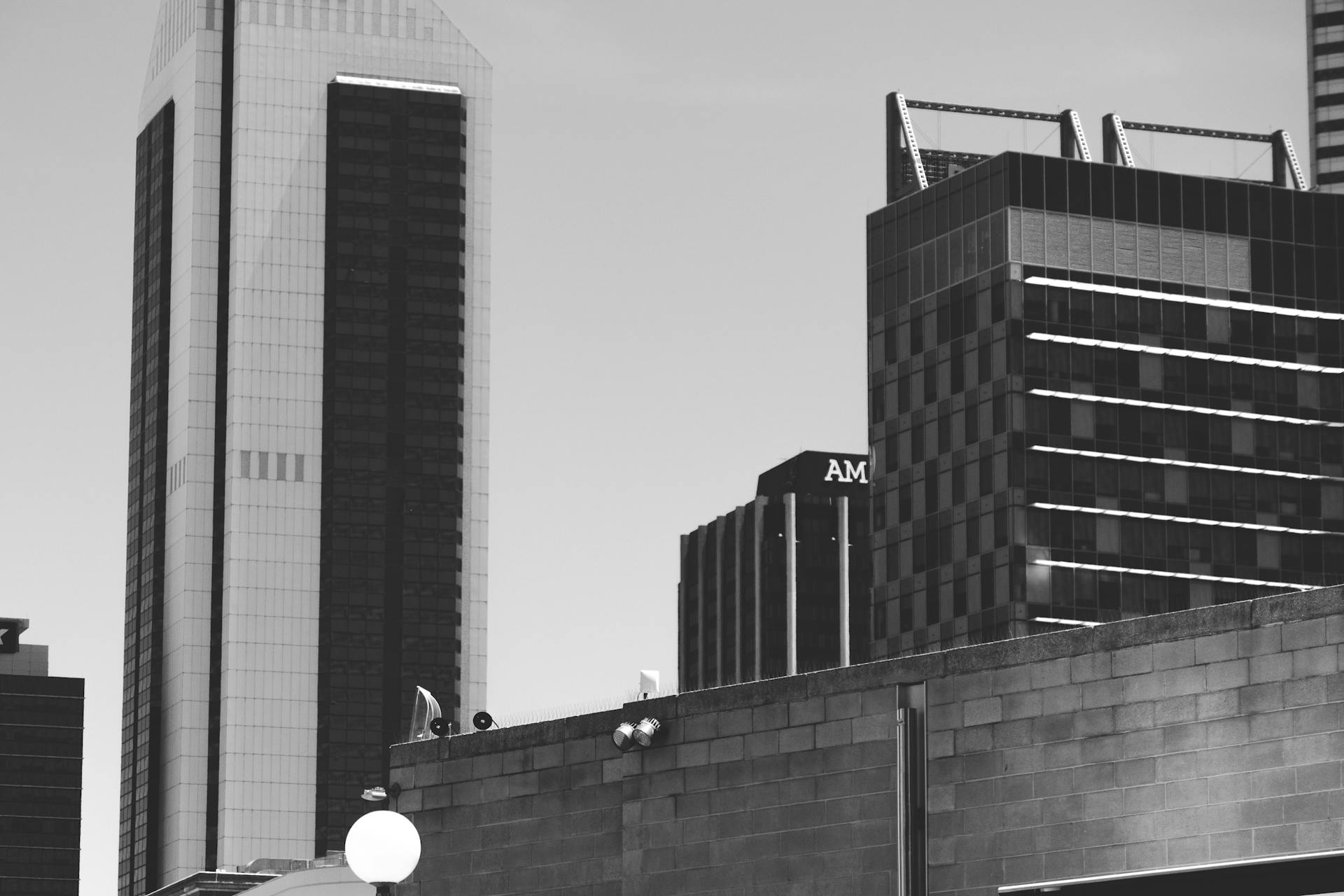 Black and white exteriors of different modern buildings located in commercial district of city against cloudy sky