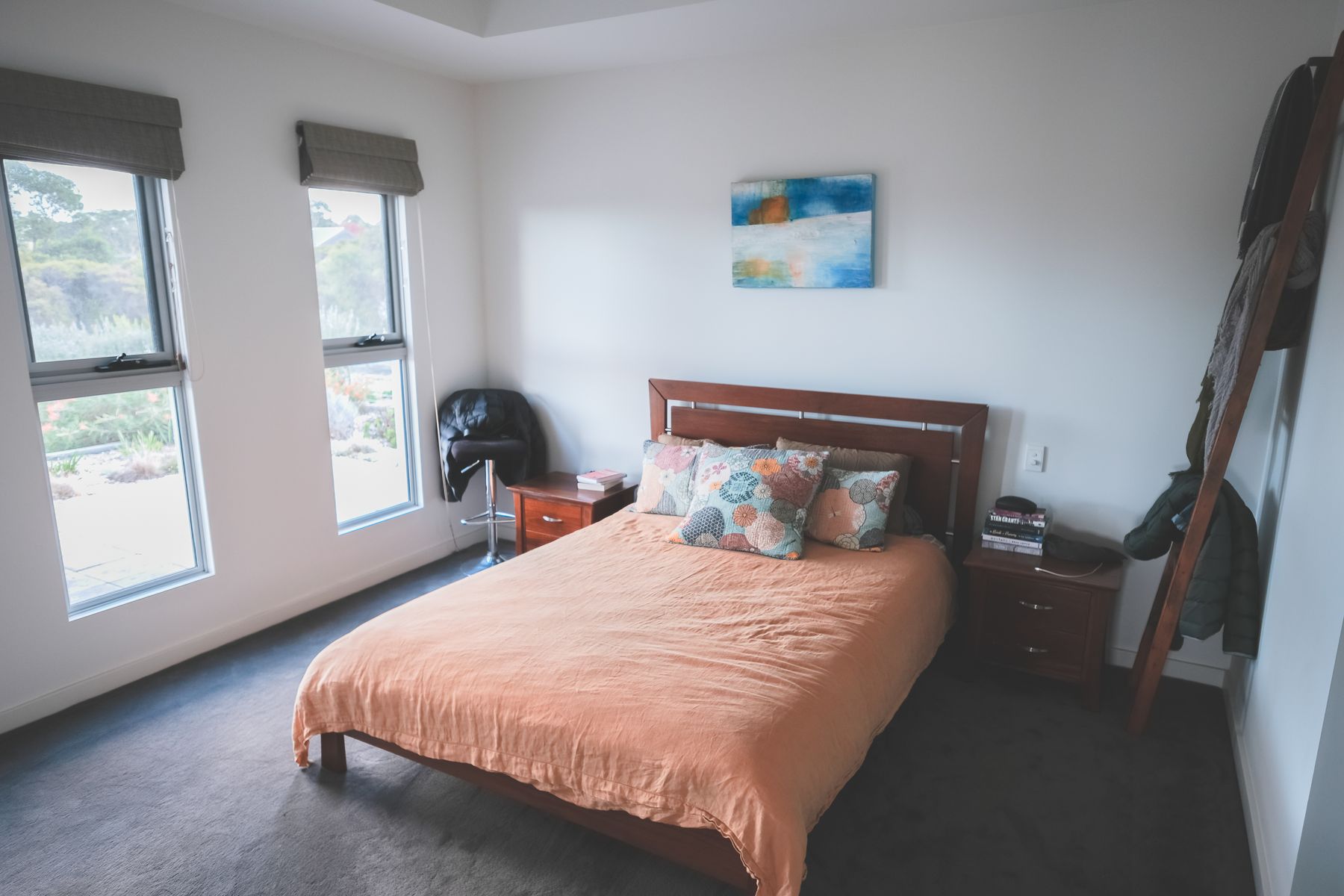 Bright modern bedroom with restrained wood furniture, a comfortable bed and daylight from a large window