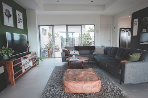 Interior of spacious living room with round coffee table placed on soft rug near comfortable sofa ad modern TV in cozy villa