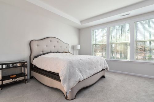 Free Bright and cozy bedroom featuring a luxurious bed and large windows with natural light. Stock Photo