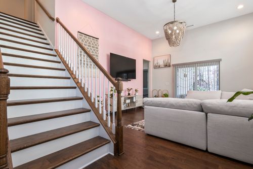 Free Bright living room with staircase, large sofa, and pastel pink wall for cozy ambiance. Stock Photo