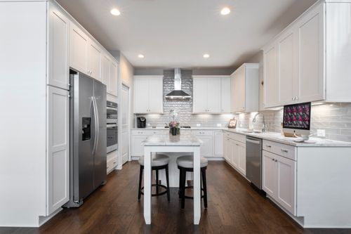 Free Spacious modern kitchen featuring white cabinets, island, and stainless steel appliances. Stock Photo