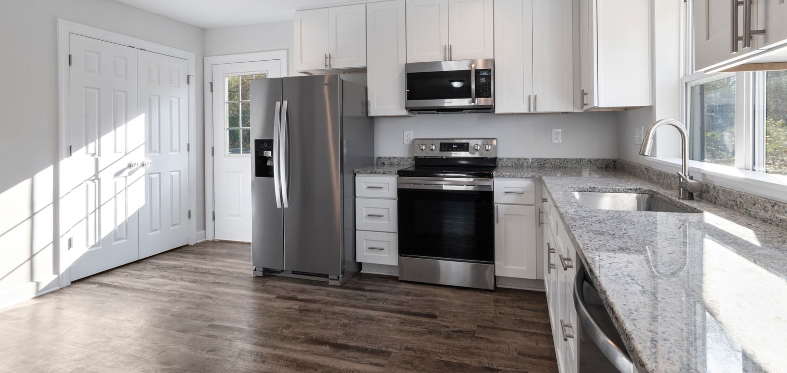Bright kitchen with white cabinets and wood floors