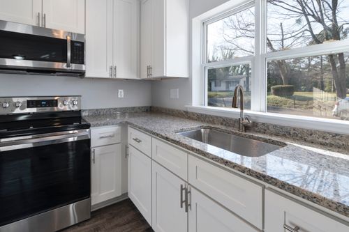Free Bright kitchen showcasing granite countertops, stainless steel appliances, and large windows. Stock Photo