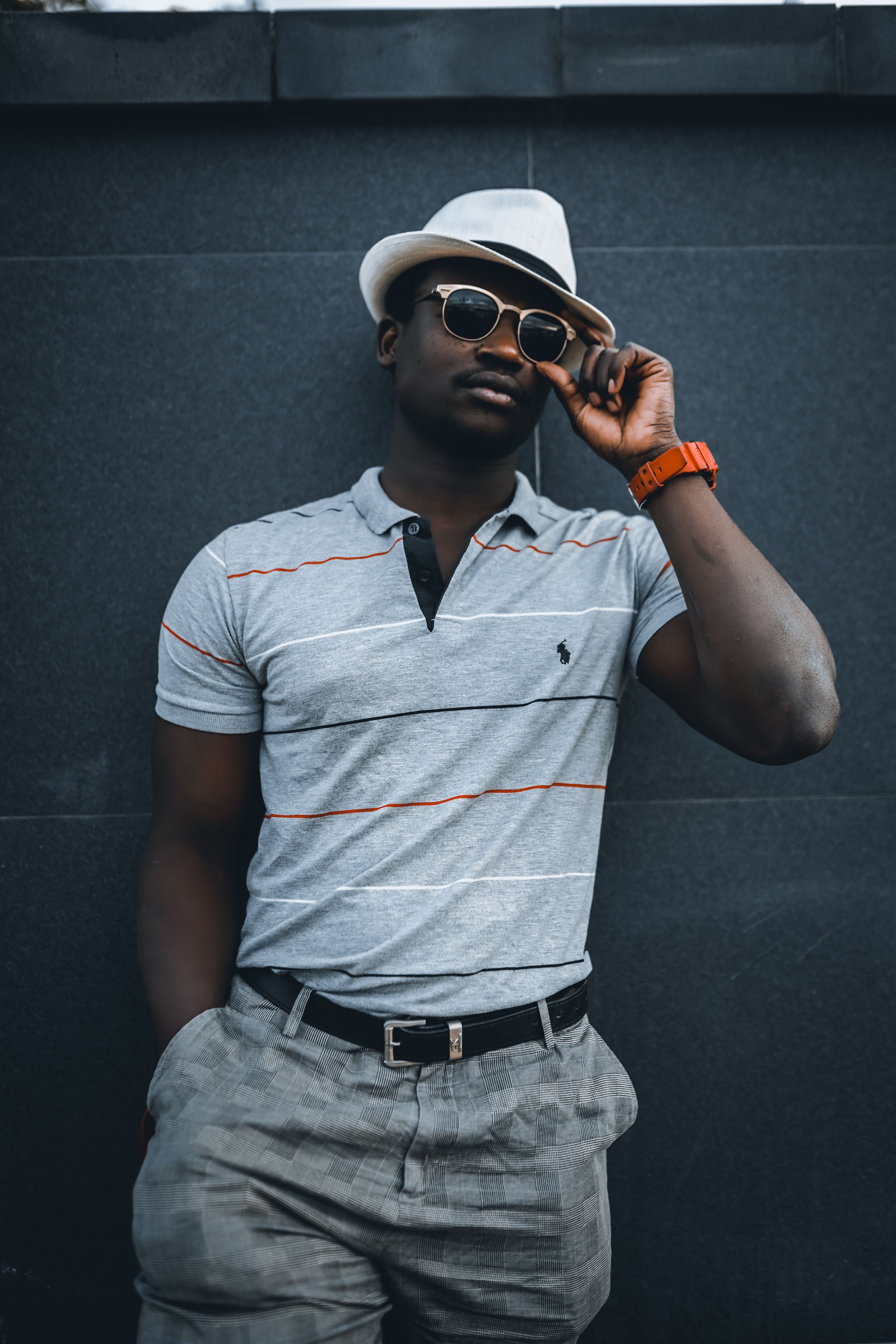 Homem afro-americano estiloso usando um chapéu e óculos de sol, posando casualmente para um retrato elegante.