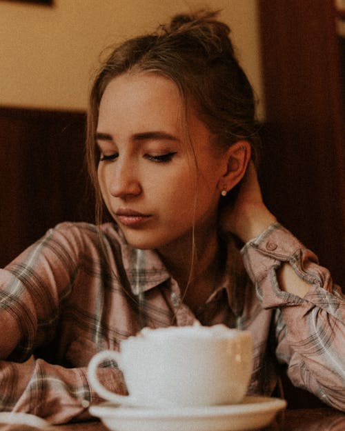 Young woman with cup of hot drink in cafe