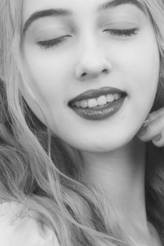 Close-up black and white portrait of a smiling woman with eyes closed, creating a serene and happy expression.