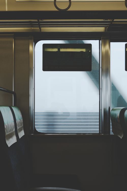 Free Interior view of public transportation with empty seats by a window showcasing a railway bridge. Stock Photo