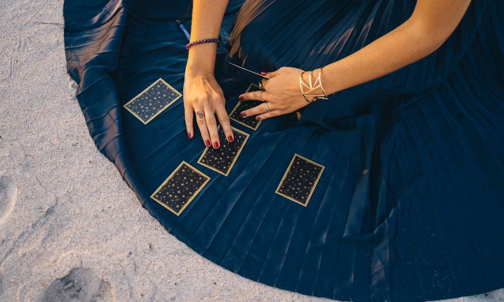 Hands shuffling an ornate tarot deck over a candlelit table before a daily one-card draw