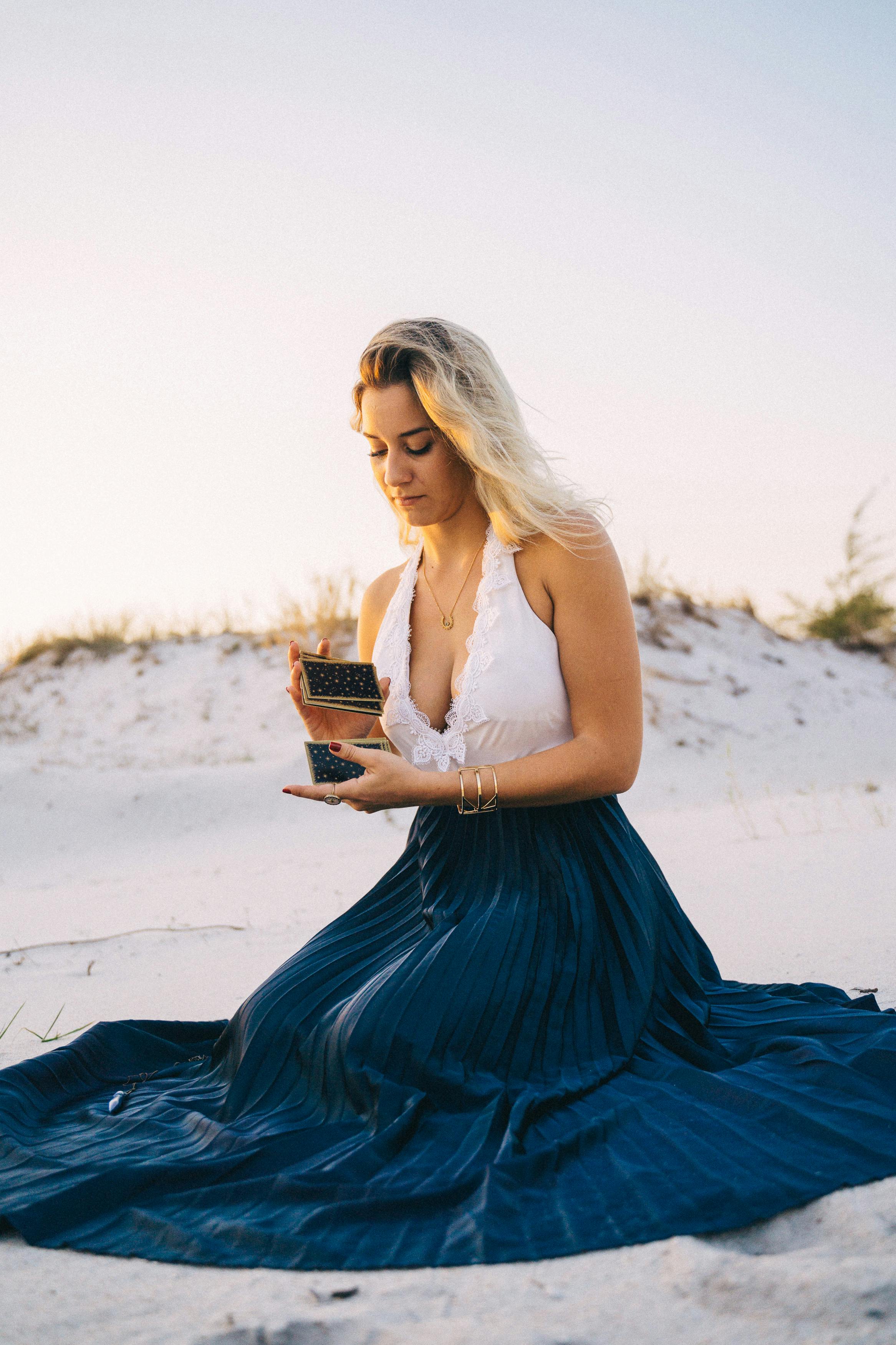 woman in white tank top and blue skirt shuffling some tarot cards