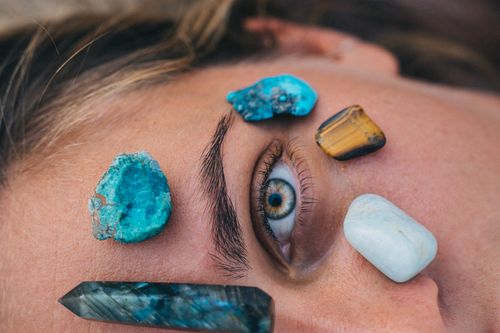 Free Close-up of a person's eye surrounded by vibrant healing stones on skin for relaxation therapy. Stock Photo