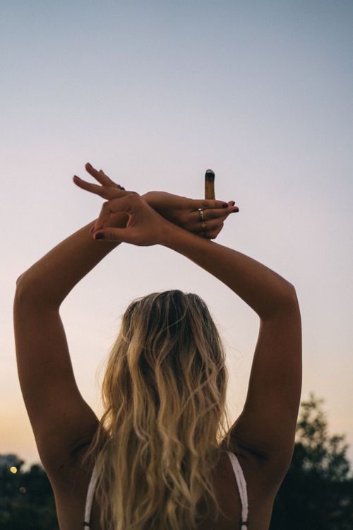Free Woman raising hands in a peaceful gesture at sunset outdoors. Stock Photo