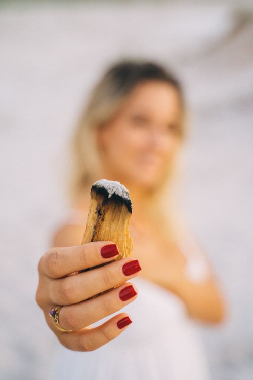 Free A woman with red nails holds a palo santo stick, blurred background creates an intimate focus. Stock Photo