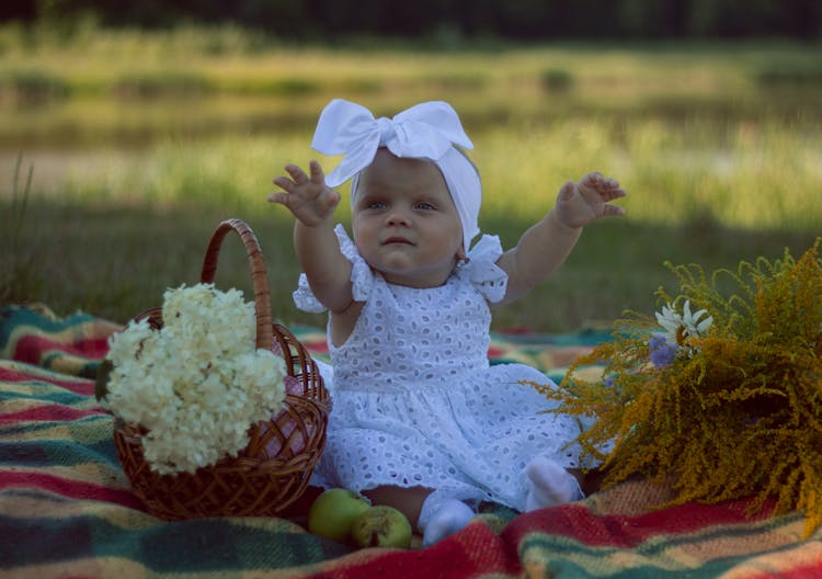 Close-Up Photo Of Baby Sitting On Picnic Blanket