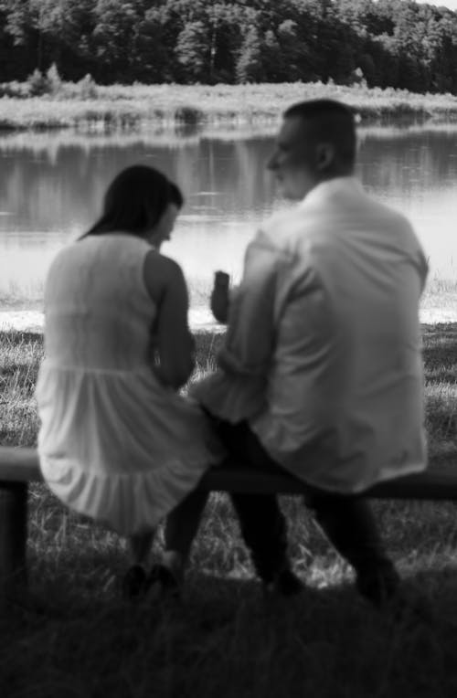 Grayscale Photo of Man and Woman Sitting at the Bench 