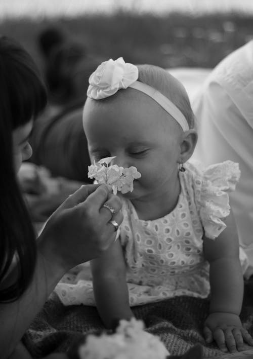 Monochrome Photo of Baby Smelling Flower