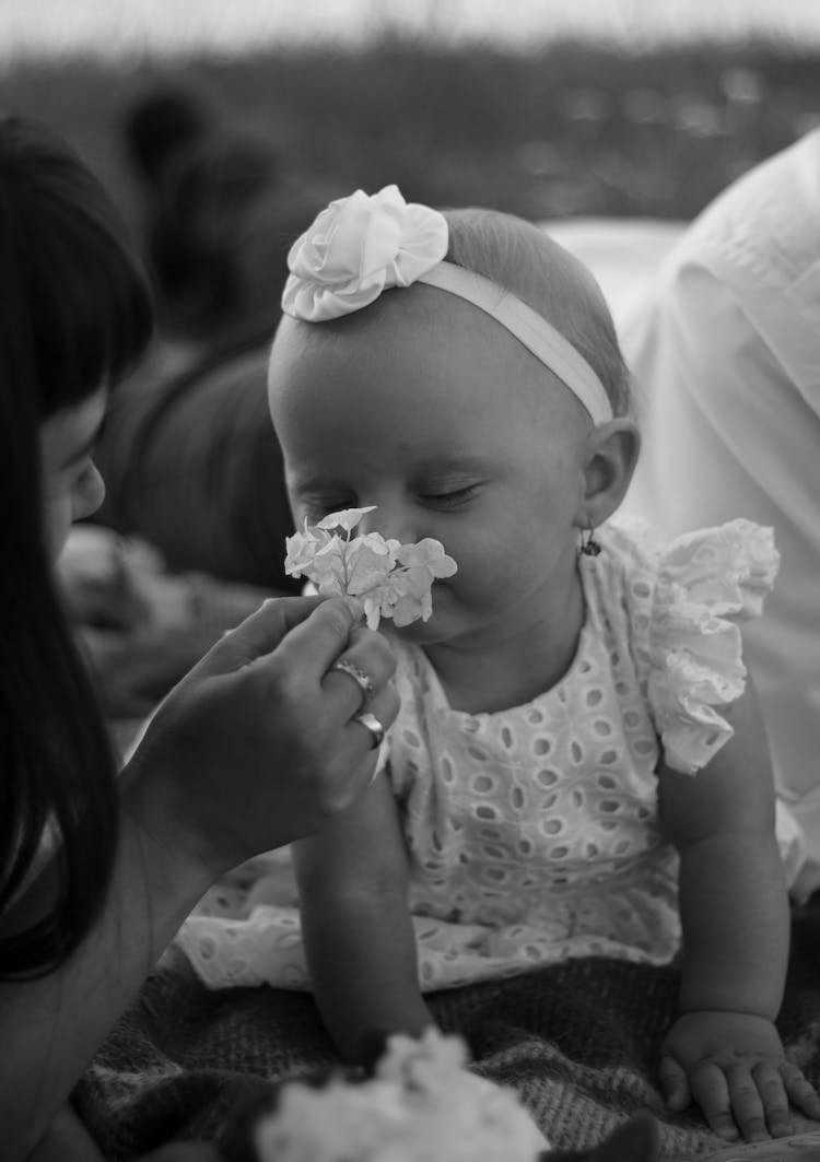 Monochrome Photo Of Baby Smelling Flower