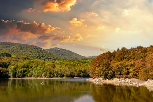 Free Tranquil landscape of Montseny National Park with colorful autumn trees and reflecting water under a dramatic sky. Stock Photo