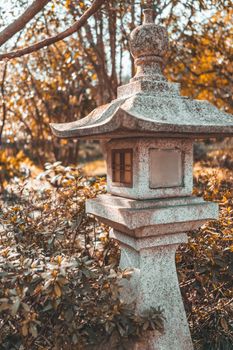 Elegant stone lantern in a Japanese garden surrounded by autumn foliage.