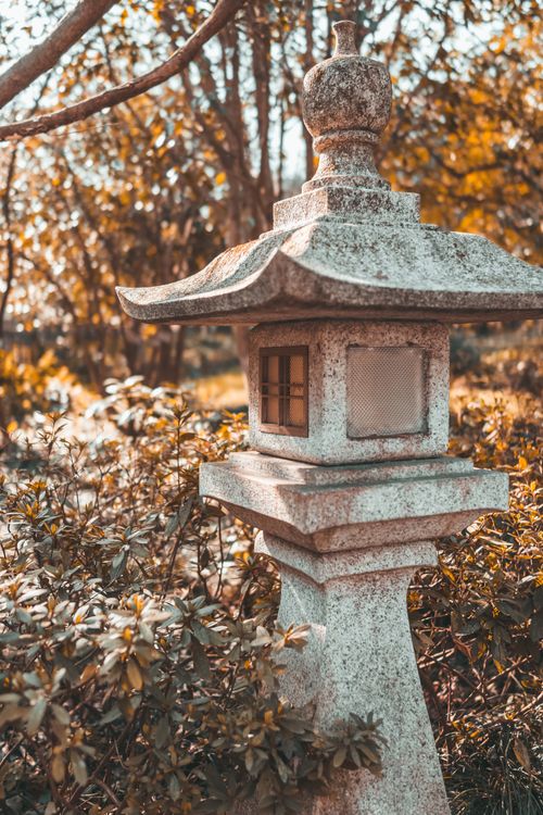 Free Elegant stone lantern in a Japanese garden surrounded by autumn foliage. Stock Photo