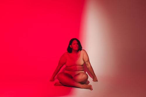 Free Empowering studio portrait of a plus-size woman embracing body positivity in striking red light. Stock Photo