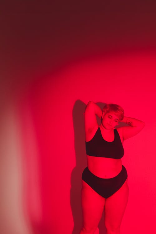 A Woman in Underwear Posing Under a Red Light