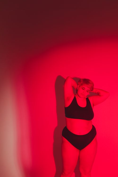 Free A confident plus size woman poses in bold red lighting, expressing body positivity. Stock Photo