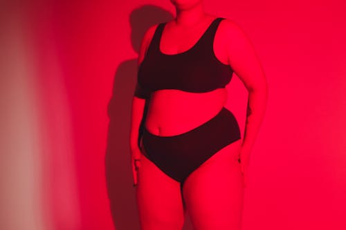 A Woman in Underwear Posing Under a Red Light