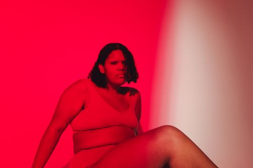 Free Confident plus-size woman poses in bold studio lighting, embracing body positivity. Stock Photo
