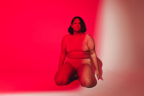 Free Empowering studio portrait of a plus-size woman embracing body positivity under red lighting. Stock Photo