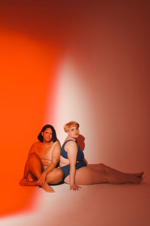 Free Two women embracing body positivity in a vibrant studio setting. Stock Photo