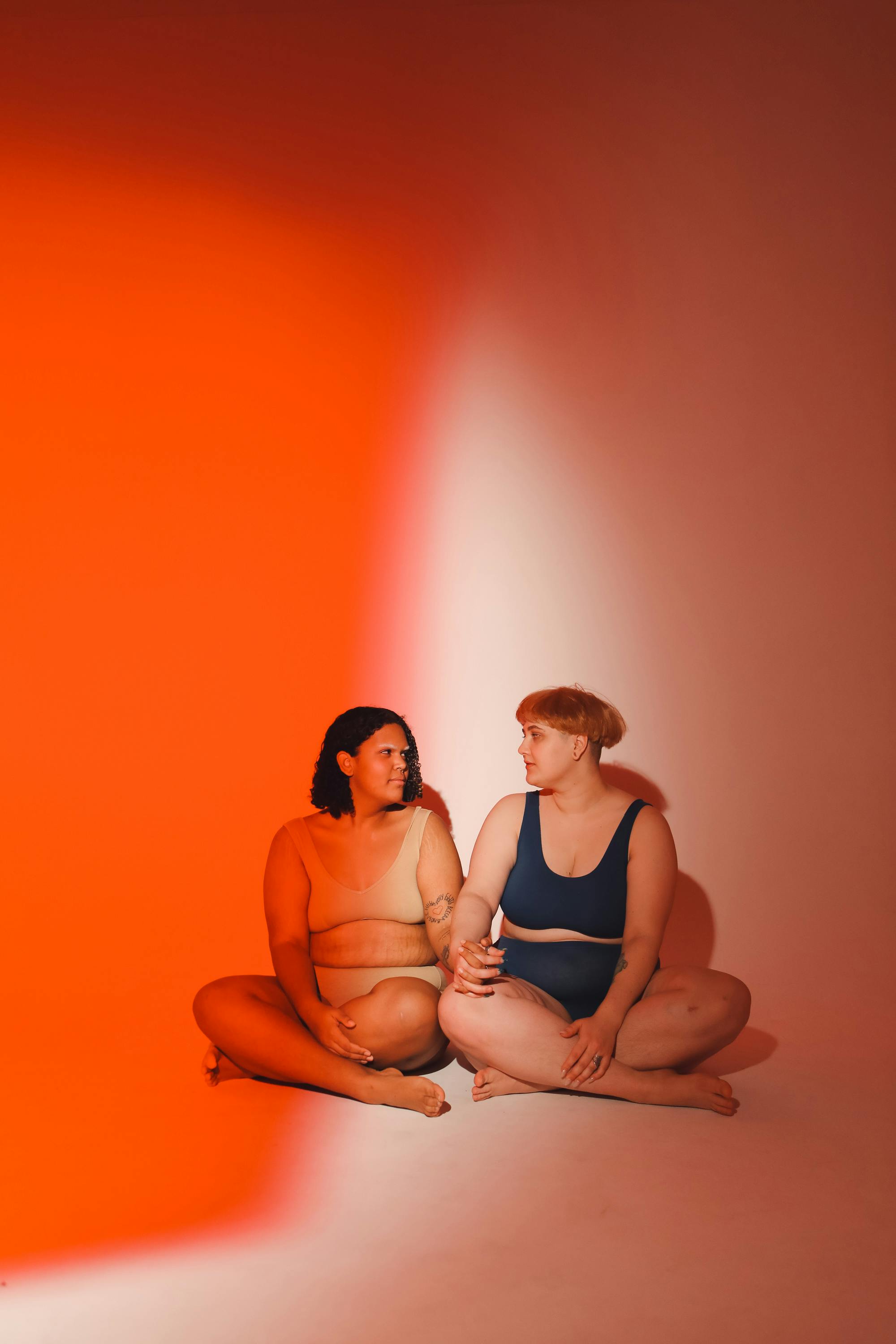 Two women sitting together in a studio, promoting body positivity.